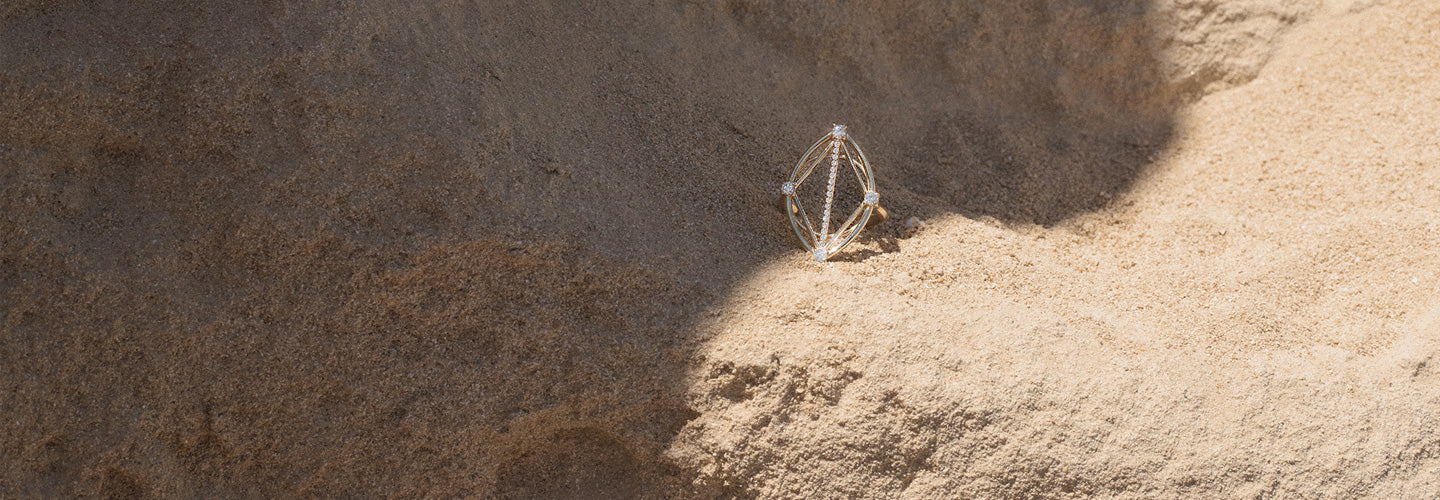Geometric gold ring on a textured  stone beige surface
